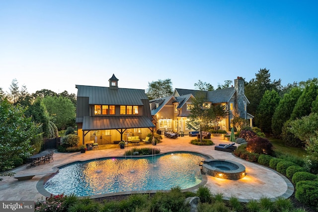 6529 Sothoron Rd, Mclean, VA 22101 - back of house at dusk featuring a standing seam roof, an outdoor hangout area, a patio, and a pool with connected hot tub
