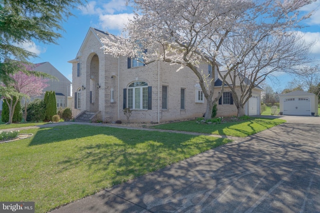 view of front of home with brick siding, concrete driveway, and a front yard