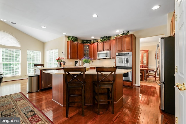 128 Bay Club Pkwy, North East, MD 21901 - kitchen featuring appliances with stainless steel finishes, light countertops, dark wood-style flooring, glass insert cabinets, and vaulted ceiling