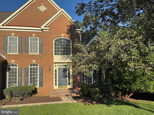 view of front of house featuring brick siding and a front yard