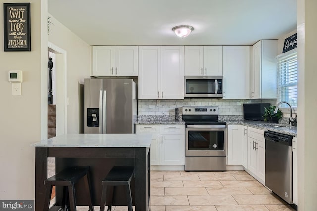 1201 Cobb Rd, Baltimore, MD 21208 - kitchen with stainless steel appliances, a sink, decorative backsplash, white cabinets, and light stone counters