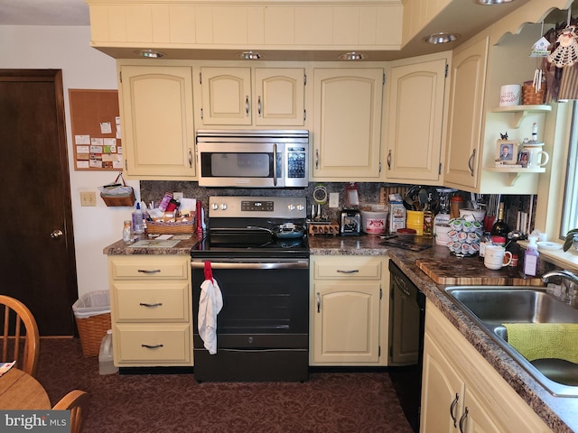 kitchen featuring stainless steel appliances, a sink, dark countertops, decorative backsplash, and cream cabinets