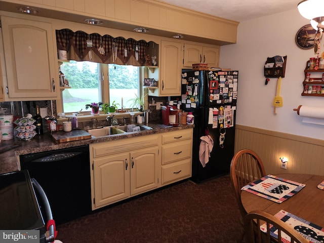 kitchen with black appliances, a sink, a wainscoted wall, and dark countertops