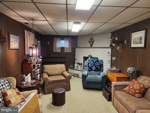 carpeted living room featuring wood walls and a paneled ceiling