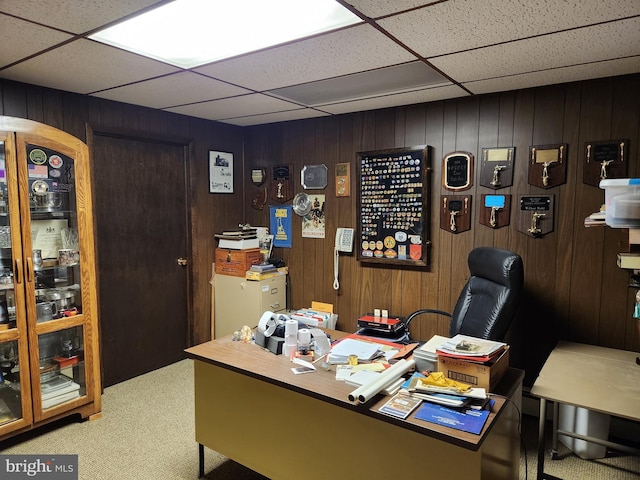 office featuring carpet flooring, a drop ceiling, and wooden walls