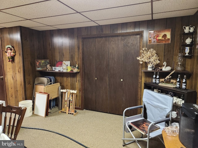 office space with carpet floors, wood walls, and a drop ceiling