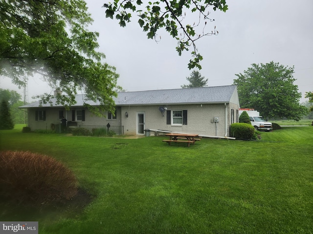 rear view of house with a lawn and brick siding