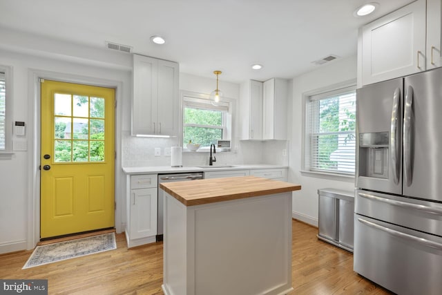 16 E Monroe Ave, Alexandria, VA 22301 - kitchen featuring stainless steel appliances, wood counters, white cabinetry, light wood-style floors, and decorative backsplash