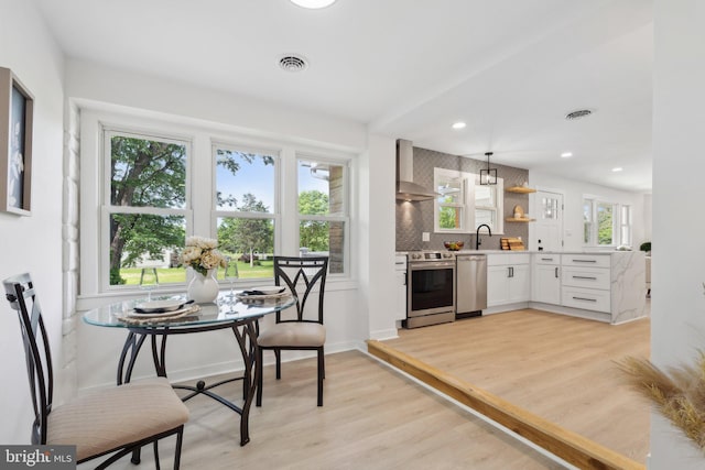 214 Dillard Ct, Front Royal, VA 22630 - kitchen featuring appliances with stainless steel finishes, wall chimney exhaust hood, light countertops, light wood-style floors, and open shelves