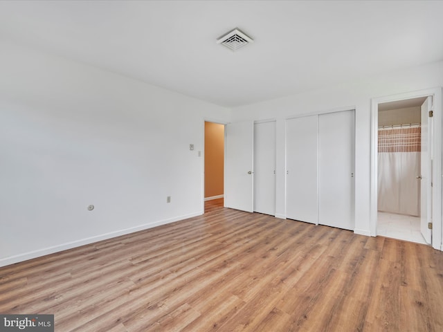 719 Loblolly Ln, Reading, PA 19607 - unfurnished bedroom featuring wood finished floors, two closets, baseboards, and connected bathroom