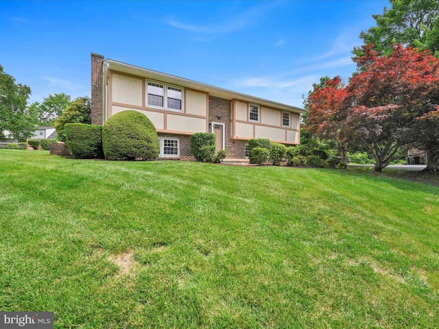719 Loblolly Ln, Reading, PA 19607 - split foyer home featuring stucco siding, a front yard, brick siding, and a chimney