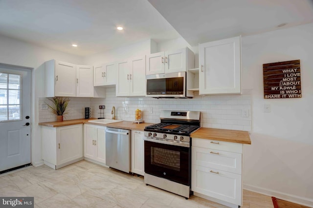 1625 Belt St, Baltimore, MD 21230 - kitchen with appliances with stainless steel finishes, butcher block countertops, a sink, white cabinetry, and tasteful backsplash