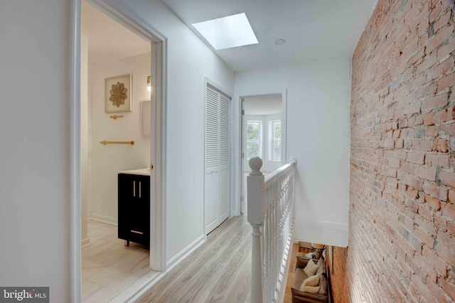 1625 Belt St, Baltimore, MD 21230 - corridor with a skylight, an upstairs landing, brick wall, and light wood-style flooring