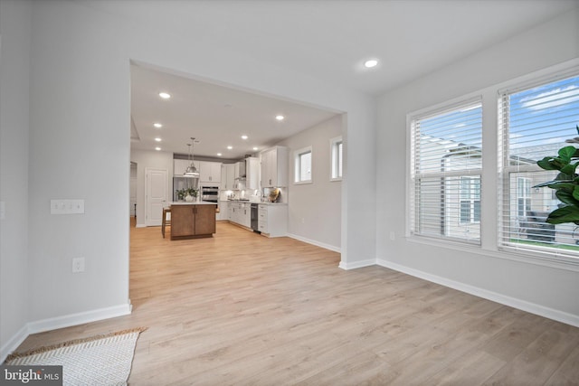 15741 Gardenia Ridge Way, Haymarket, VA 20169 - kitchen featuring open floor plan, a center island, light wood-type flooring, baseboards, and white cabinetry