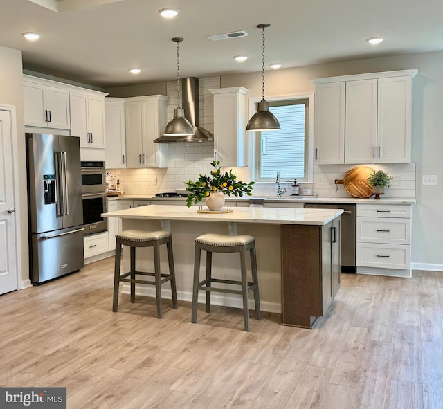 15741 Gardenia Ridge Way, Haymarket, VA 20169 - kitchen featuring appliances with stainless steel finishes, wall chimney range hood, a center island, light countertops, and backsplash