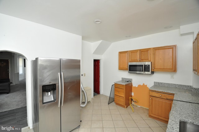 1249 Morse St NE, Washington, DC 20002 - kitchen with stainless steel appliances, arched walkways, light stone counters, brown cabinets, and light tile patterned floors