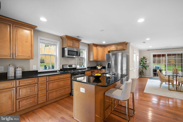 3949 Taney Ave, Alexandria, VA 22304 - kitchen featuring stainless steel appliances, a sink, light wood-style floors, brown cabinets, and a kitchen breakfast bar
