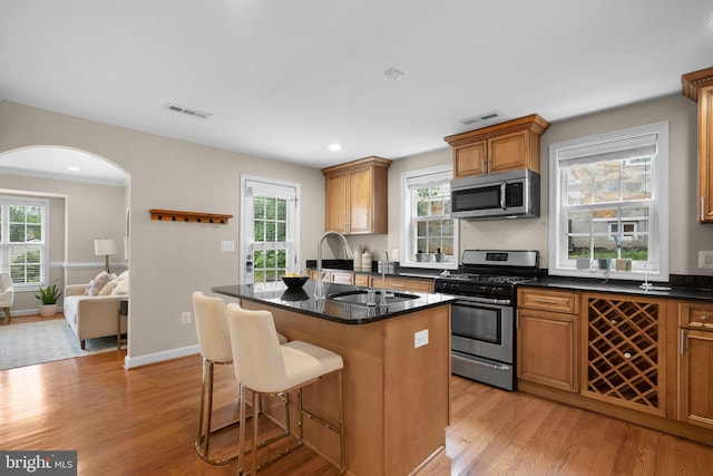3949 Taney Ave, Alexandria, VA 22304 - kitchen with appliances with stainless steel finishes, light wood finished floors, arched walkways, a kitchen breakfast bar, and brown cabinets