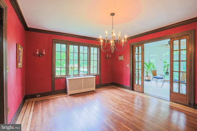 unfurnished room with radiator, wood finished floors, crown molding, a chandelier, and baseboards