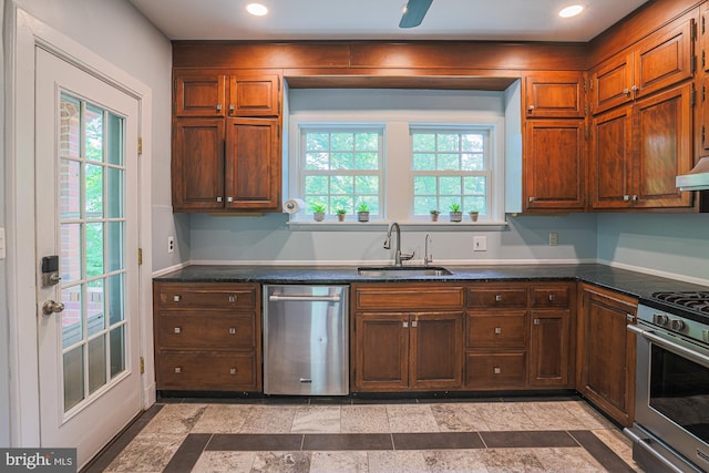 kitchen featuring appliances with stainless steel finishes, a sink, dark countertops, plenty of natural light, and recessed lighting