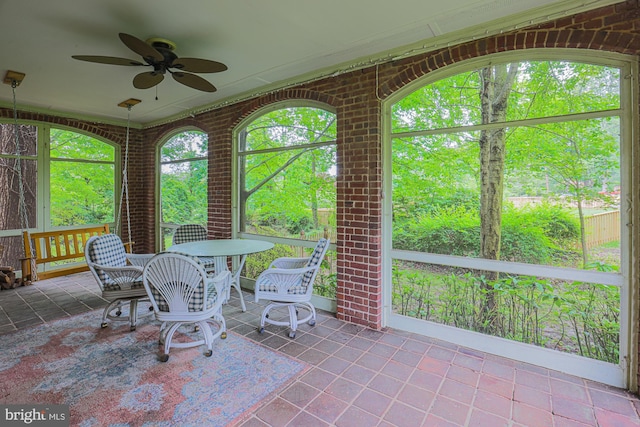 sunroom / solarium with a ceiling fan and outdoor dining area