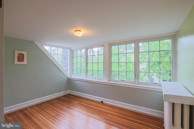 spare room with baseboards and wood finished floors