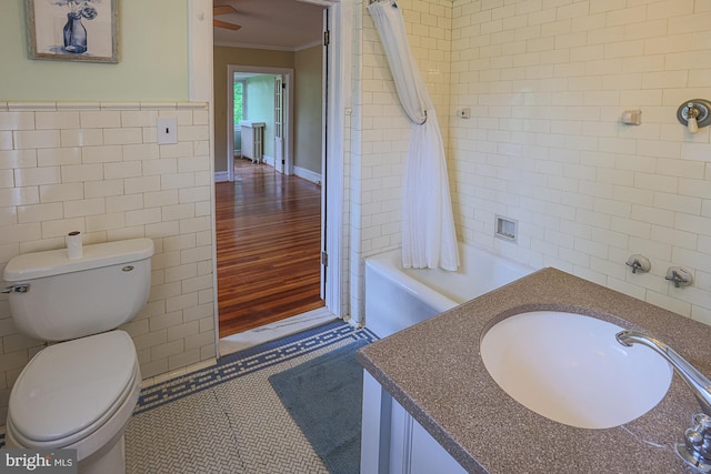 bathroom with tile walls, crown molding, vanity, toilet, and shower / bathtub combination with curtain