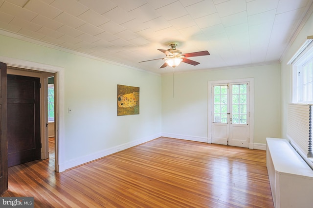 empty room featuring ornamental molding, light wood-type flooring, ceiling fan, and baseboards