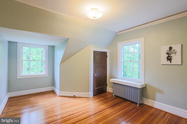 bonus room with radiator heating unit, vaulted ceiling, light wood-type flooring, and baseboards