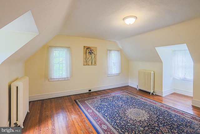 additional living space featuring radiator heating unit, vaulted ceiling, hardwood / wood-style floors, and baseboards