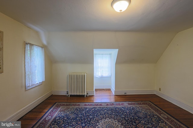 bonus room with radiator heating unit, wood finished floors, vaulted ceiling, and baseboards