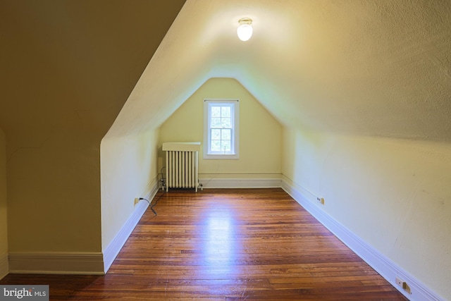 bonus room with radiator heating unit, hardwood / wood-style floors, lofted ceiling, and baseboards