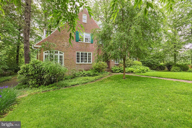 tudor home with brick siding and a front yard