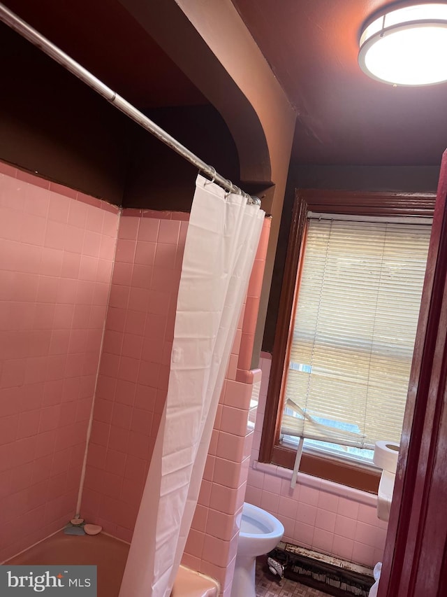 bathroom featuring tile walls, toilet, and shower / bathtub combination with curtain