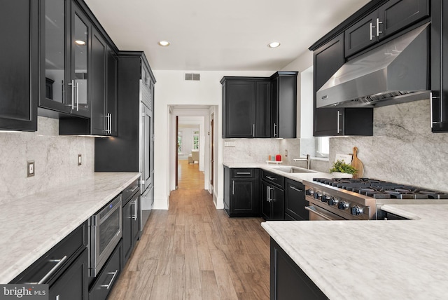 2314 20th St NW, Washington, DC 20009 - kitchen featuring under cabinet range hood, appliances with stainless steel finishes, dark cabinetry, light countertops, and a sink