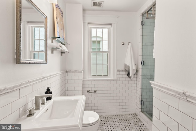 2314 20th St NW, Washington, DC 20009 - bathroom featuring tile walls, a stall shower, a wainscoted wall, a sink, and toilet