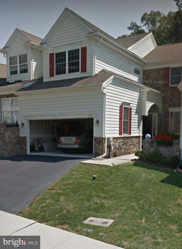 view of side of home featuring a garage, stone siding, a lawn, and asphalt driveway