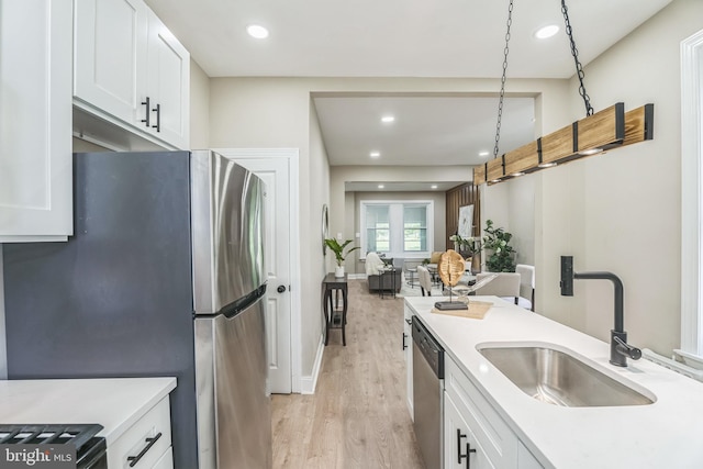 kitchen featuring a sink, light wood-style floors, appliances with stainless steel finishes, light countertops, and white cabinets