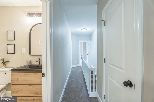 corridor with carpet flooring, baseboards, and a sink