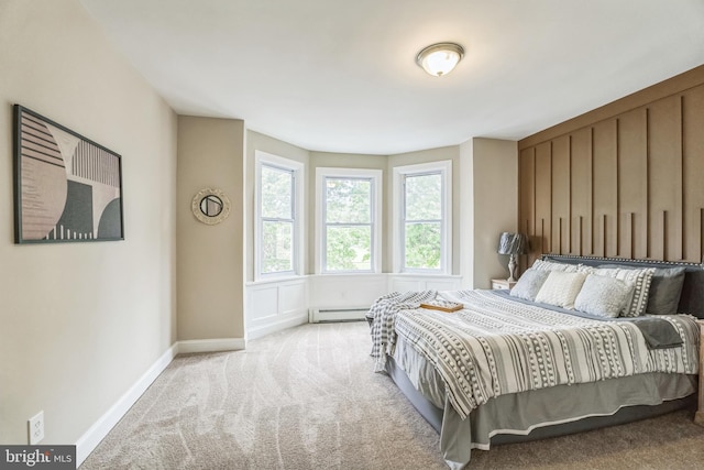 bedroom with a baseboard heating unit, carpet floors, and baseboards