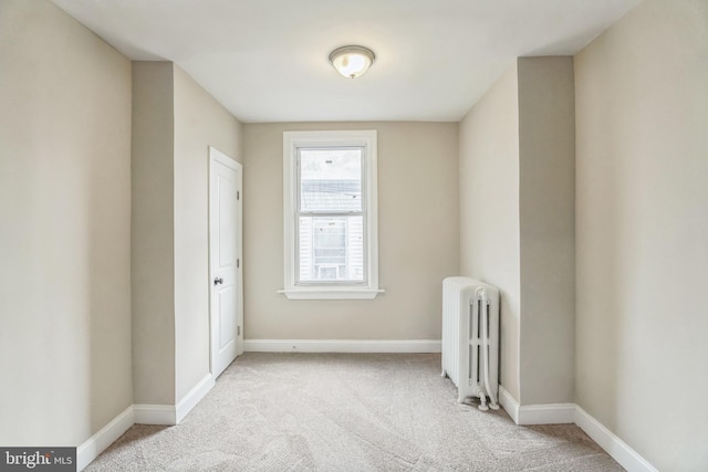 carpeted spare room with radiator heating unit and baseboards