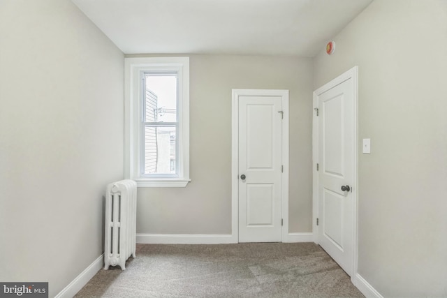carpeted empty room with radiator heating unit and baseboards