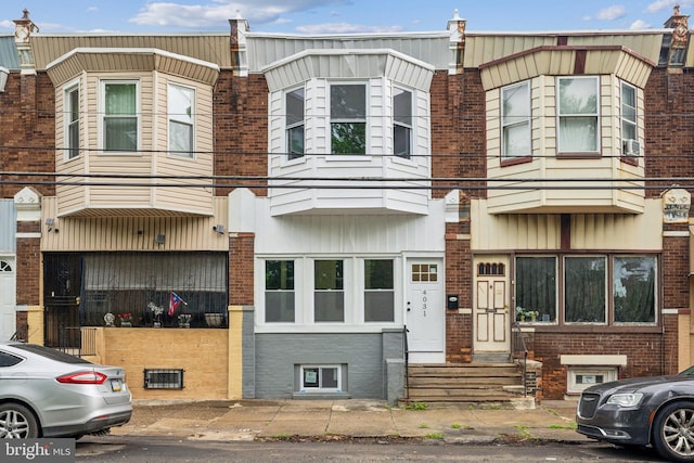 townhome / multi-family property featuring entry steps, brick siding, and cooling unit