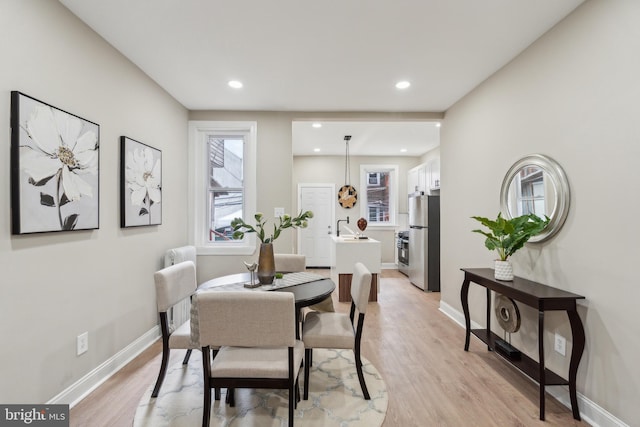 dining room with light wood-type flooring, recessed lighting, plenty of natural light, and baseboards