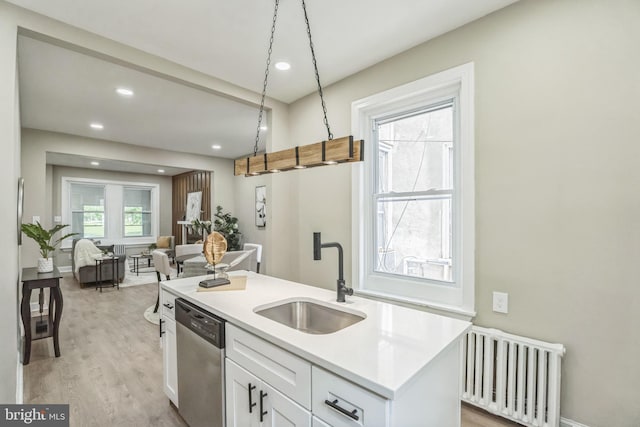 kitchen with radiator heating unit, a sink, stainless steel dishwasher, white cabinetry, and recessed lighting