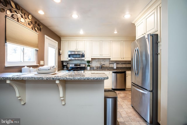 235 George Dye Rd, Hamilton, NJ 08690 - kitchen featuring stainless steel appliances, a sink, a kitchen bar, decorative backsplash, and light stone countertops