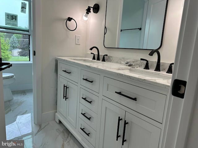 full bathroom with marble look tiles, baseboards, double vanity, and toilet