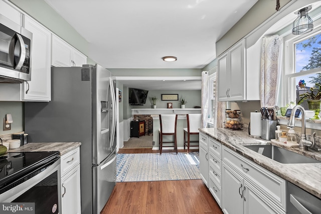 230 Aqua Ln, Delran, NJ 08075 - kitchen featuring a sink, stainless steel appliances, white cabinetry, wood finished floors, and light stone counters