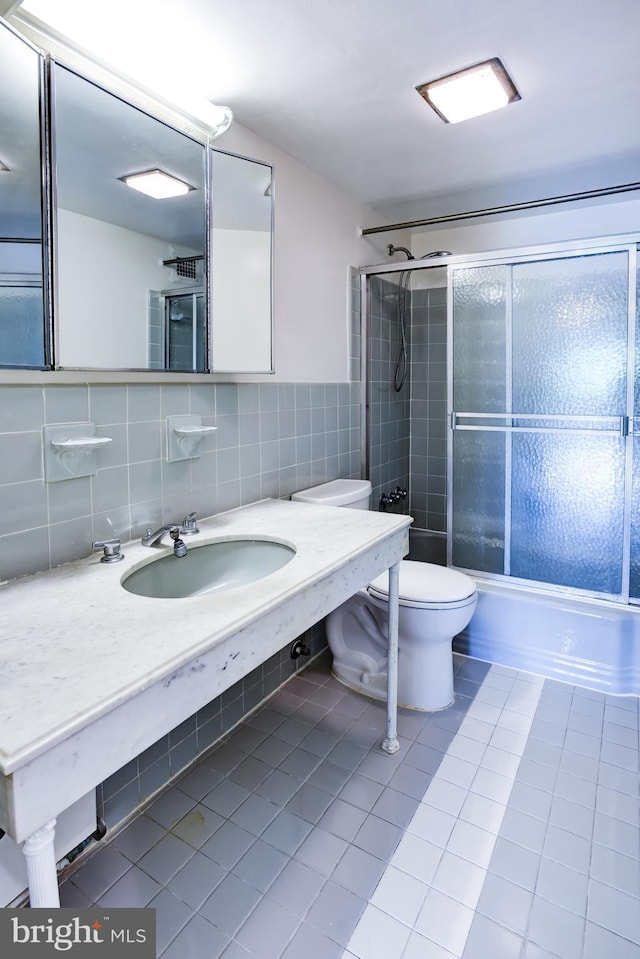 4201 Cathedral Ave NW Unit 1004E, Washington, DC 20016 - full bath with tile patterned floors, toilet, tile walls, bath / shower combo with glass door, and a sink