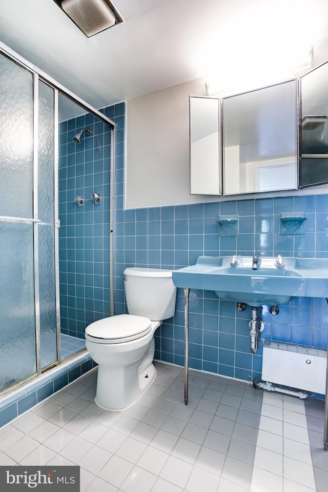 4201 Cathedral Ave NW Unit 1004E, Washington, DC 20016 - bathroom featuring tile patterned flooring, a shower stall, tile walls, toilet, and a sink
